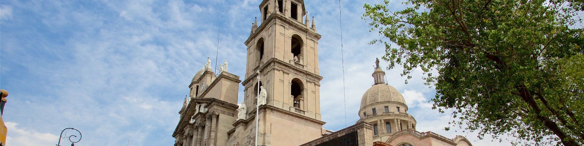 Una iglesia histórica con un campanario y una cúpula, rodeada de calles urbanas y peatones.