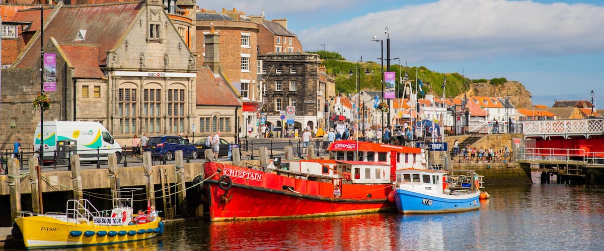 A harbor with colorful boats, a historic building, and a clear sky.