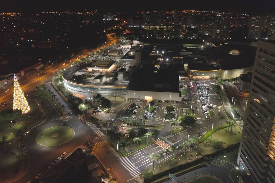 A cityscape at night with a prominent roundabout, illuminated buildings, and a large parking structure.