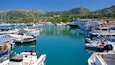Uma marina com vários barcos atracados, cercada por colinas e edifícios.