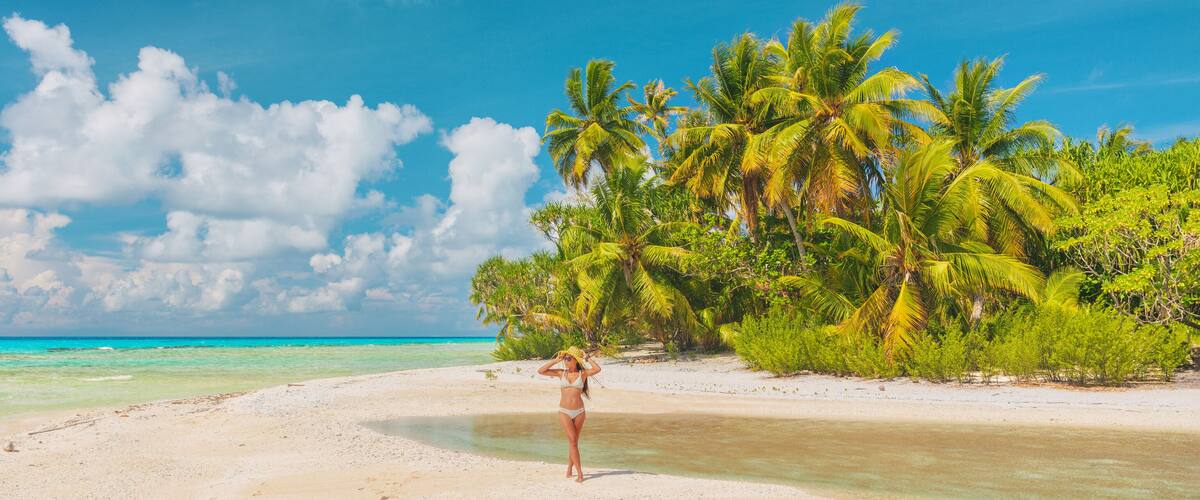 Beach vacation paradise woman tourist walking alone on remote island in the tuamotu islands, French Polynesia. Luxury travel destination. Panoramic banner.