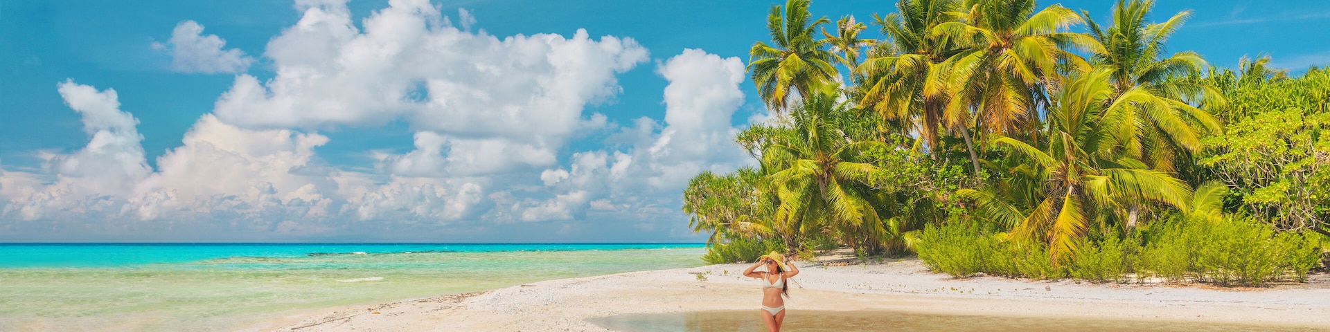 Beach vacation paradise woman tourist walking alone on remote island in the tuamotu islands, French Polynesia. Luxury travel destination. Panoramic banner.