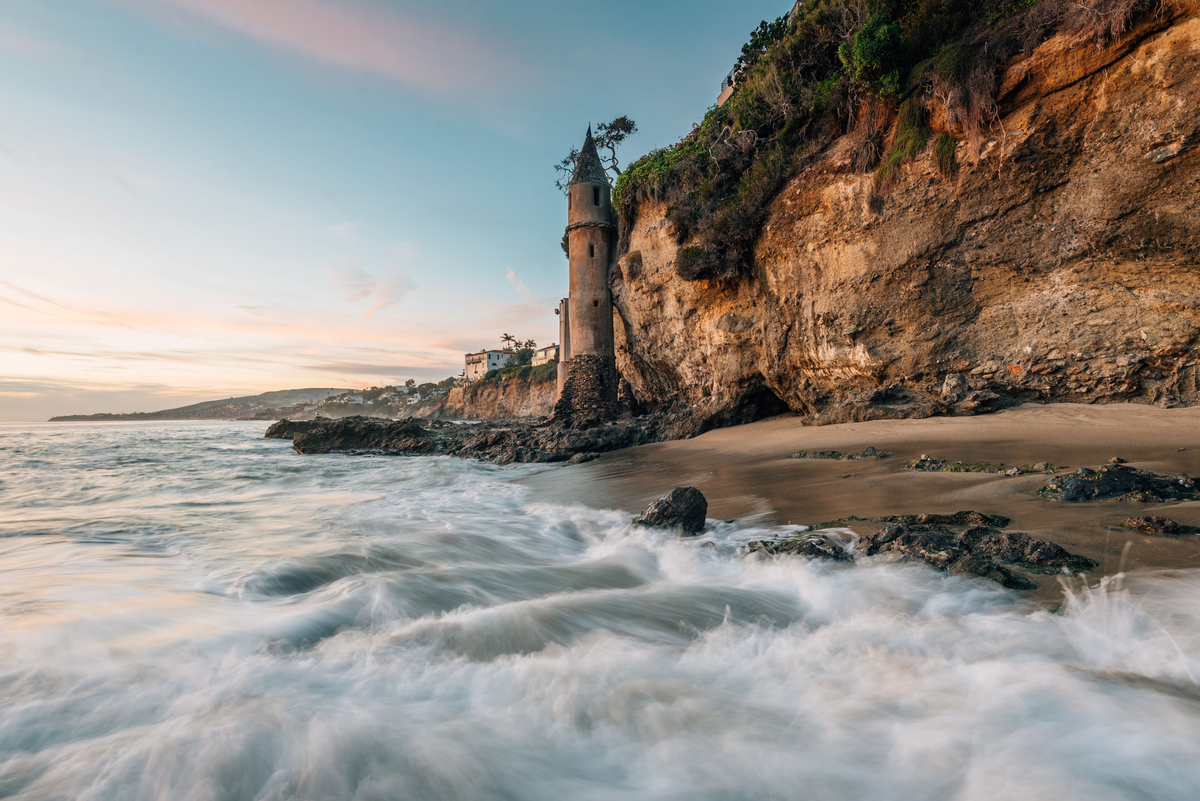 Waves in the Pacific Ocean and the Pirate Tower at sunset, at Victoria Beach, Laguna Beach, California