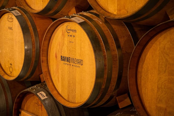 Des tonneaux en bois, remplis de vin, sont empilés les uns contre les autres.