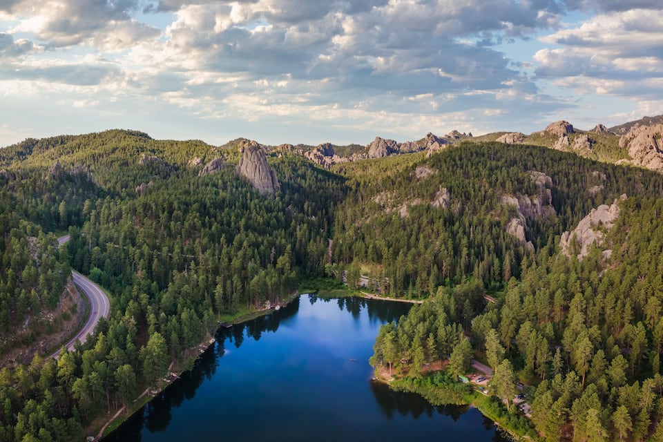 Un lago circondato da fitti boschi e montagne rocciose.