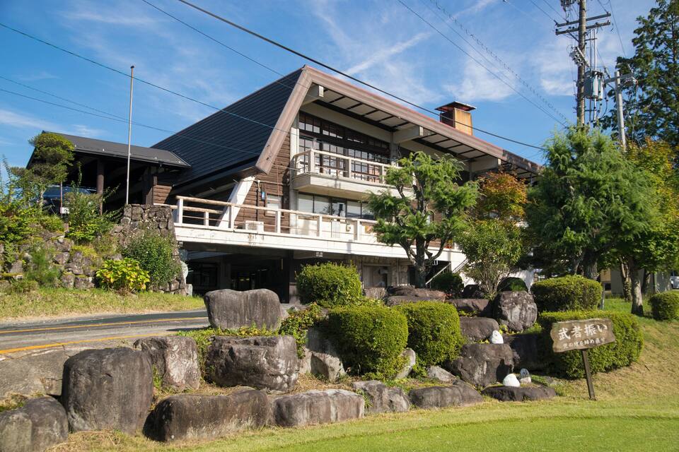 Une maison traditionnelle japonaise, avec un toit en pente, de gros rochers et une enseigne en japonais.