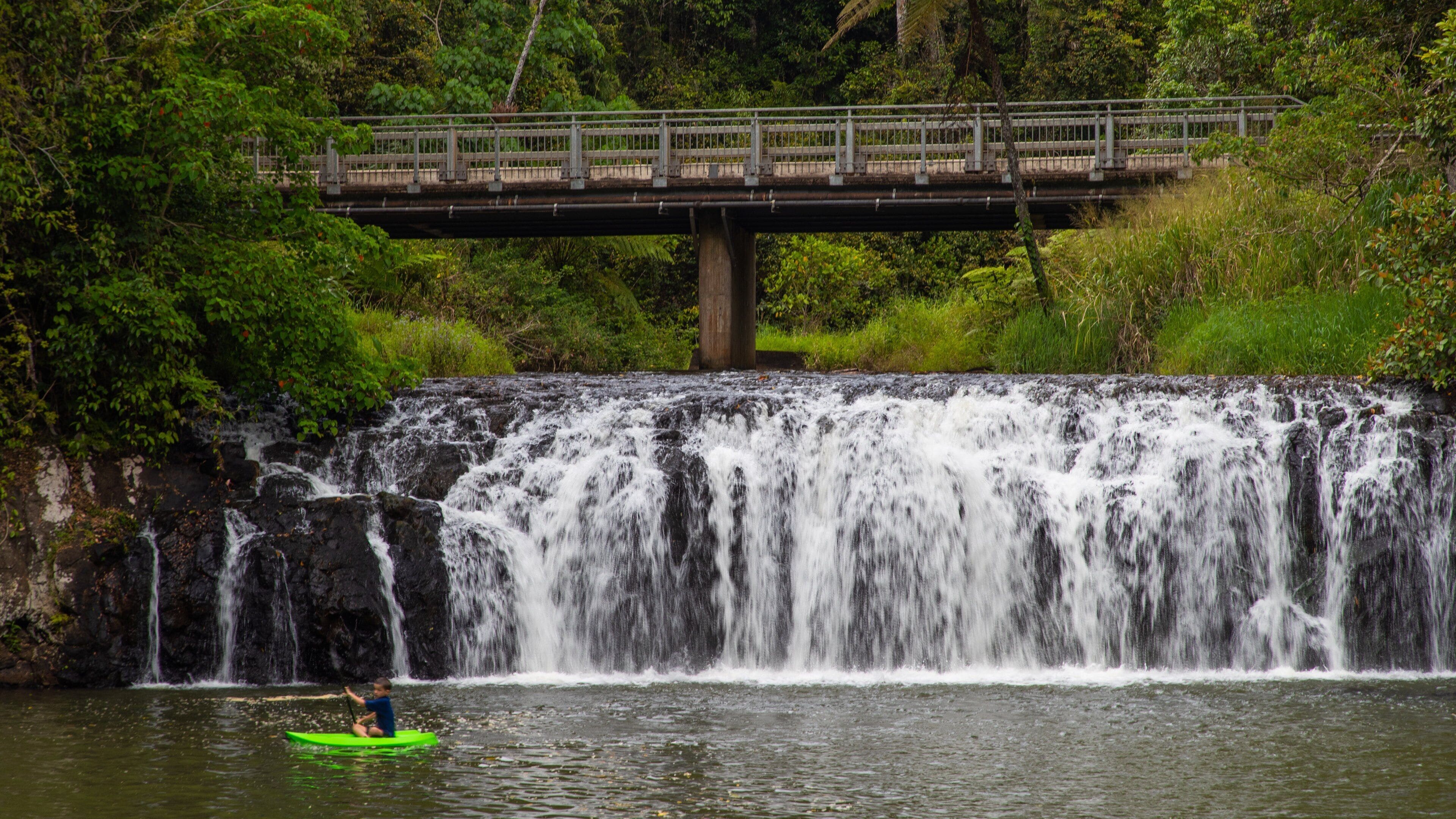Una cascada, un puente y una persona haciendo kayak.