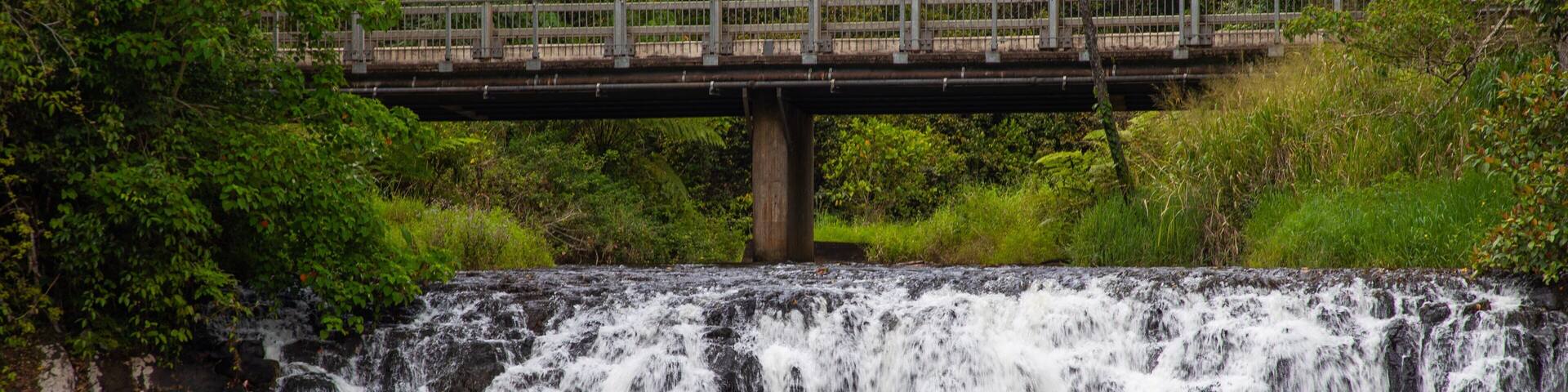 Une cascade, un pont et une personne pratiquant le kayak.
