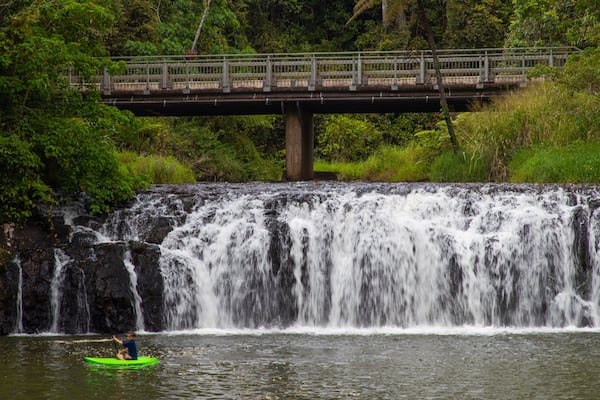 Une cascade, un pont et une personne pratiquant le kayak.