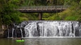 Une cascade, un pont et une personne pratiquant le kayak.