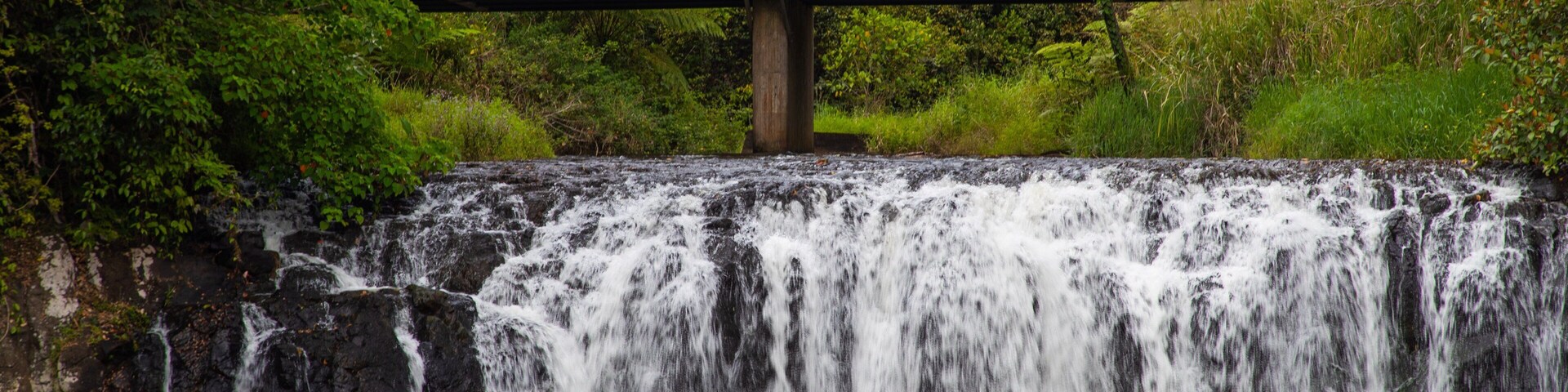 Una cascada, un puente y una persona haciendo kayak.