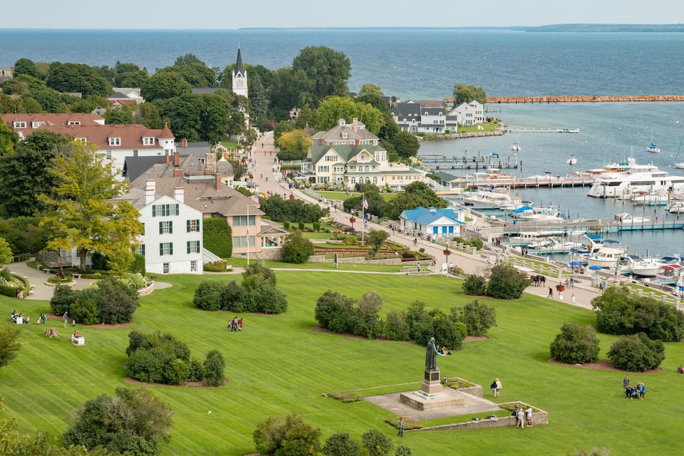 Een kustplaatsje met een jachthaven, een kerk en een standbeeld in een park.