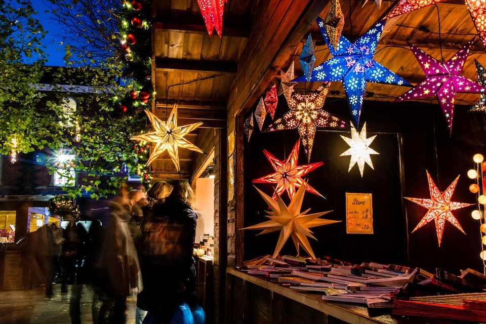 A market stall with illuminated star decorations and a sign listing prices.