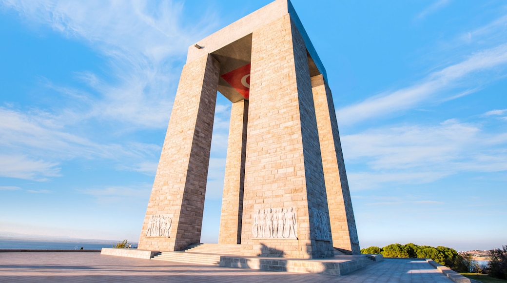 A large stone monument with a flag on top, set against a clear blue sky.