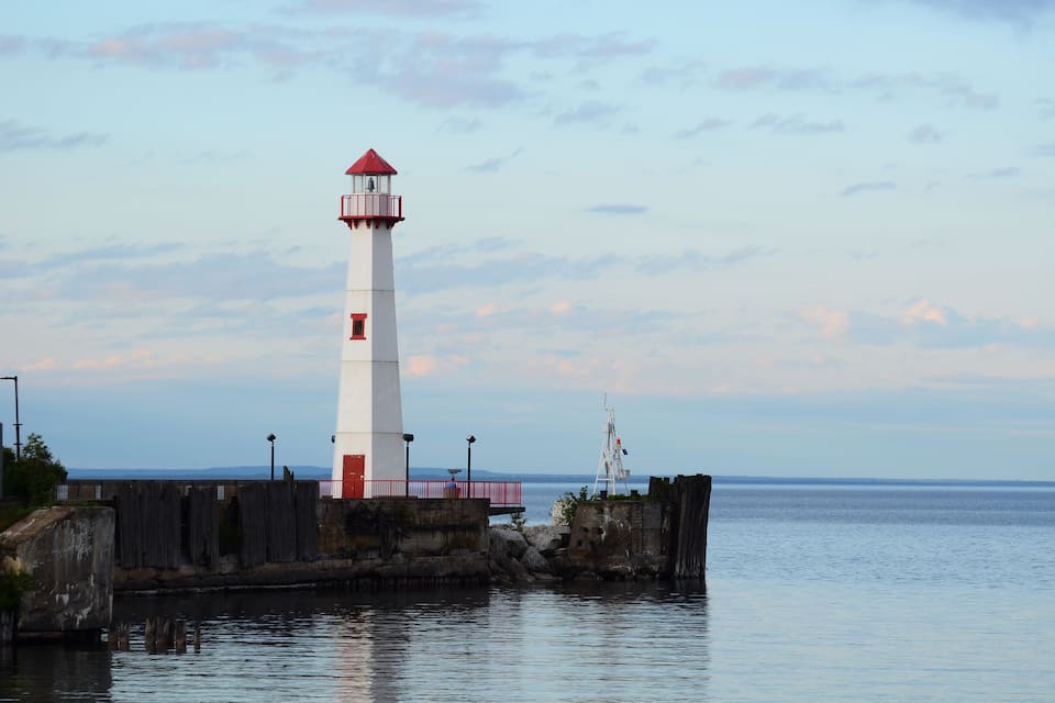 A lighthouse by the water with a red top and white body.