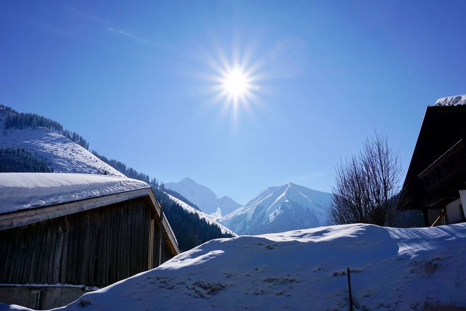 Een besneeuwd berg dorp met houten gebouwen en een helderblauwe lucht.