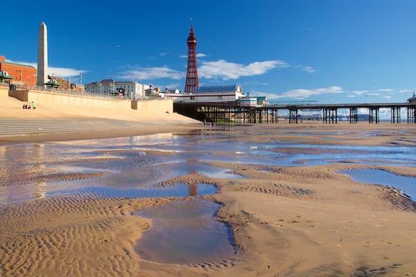 Ein Strand mit Sandbänken, einem Steg, einem Turm und einem Denkmal.
