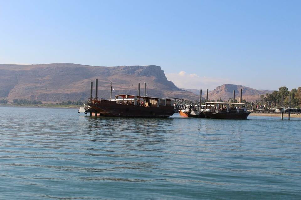 Two boats docked at a pier with a mountainous landscape in the background.