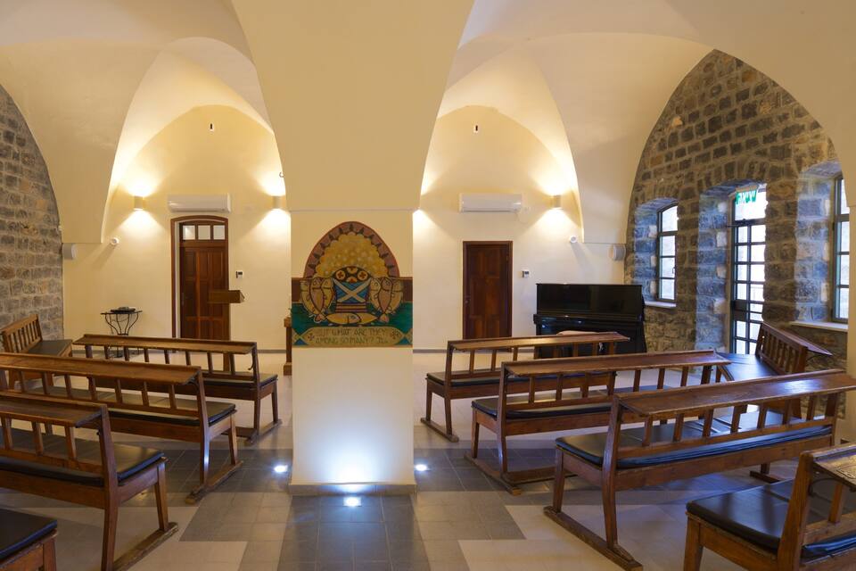 A church interior with wooden pews, a piano, and a stained glass window.