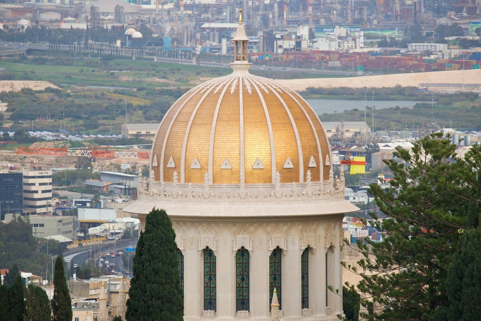 A large golden dome with a white base, surrounded by trees and urban buildings.
