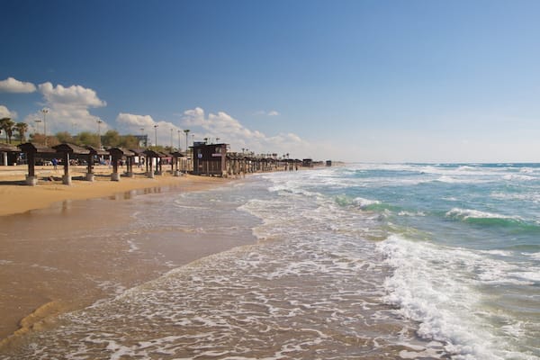 A beach with wooden structures and a clear sky.