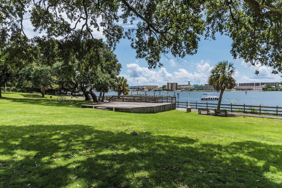 A park with a stage, picnic tables, and a waterfront view.