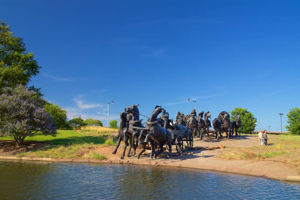 A statue of a group of people on horses by a body of water.