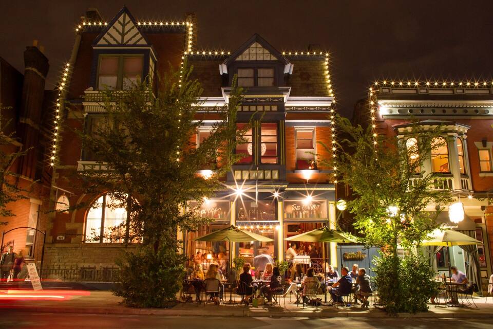 A historic building with Victorian architecture, outdoor seating, and string lights.