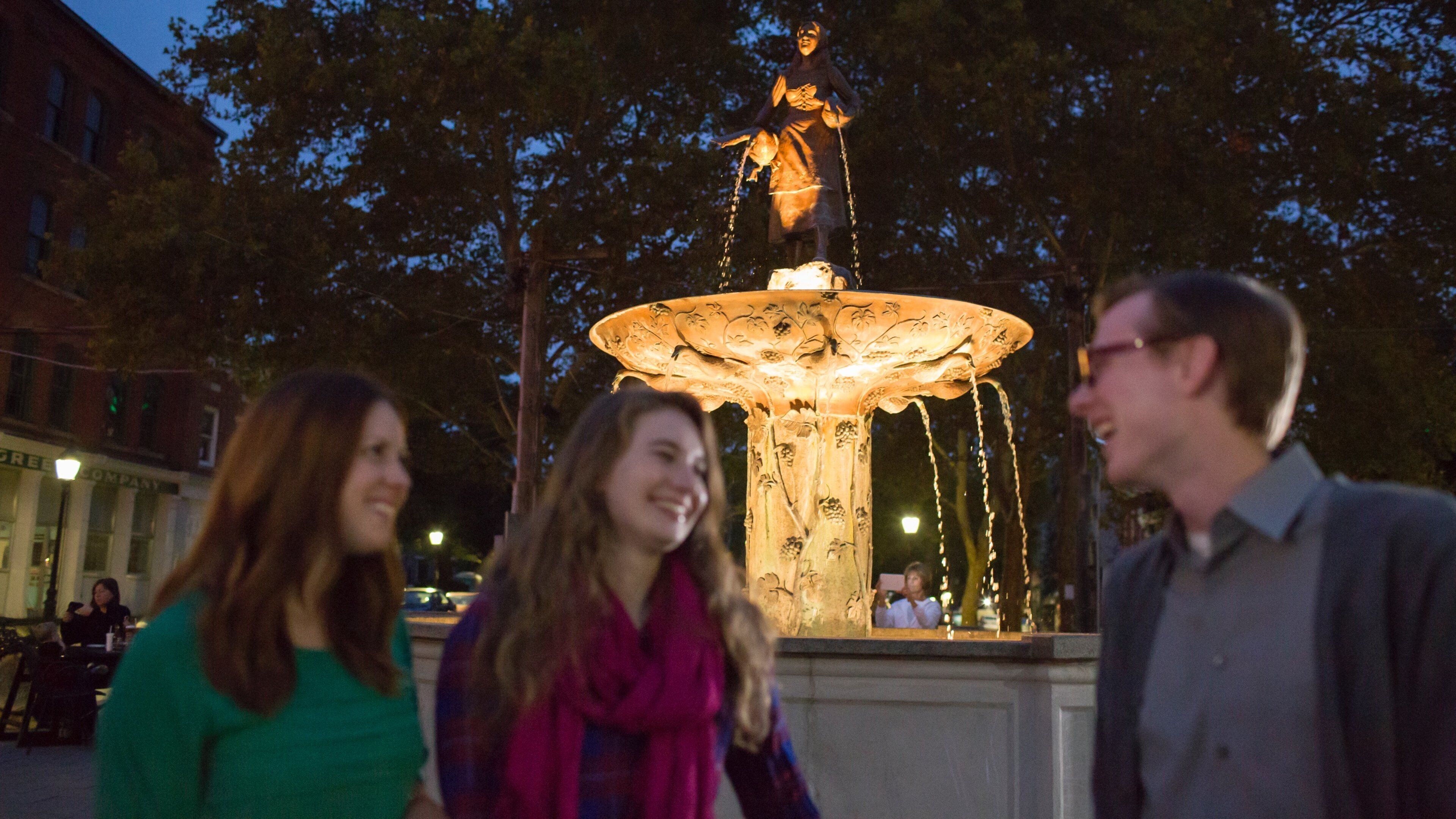 MainStrasse Village which includes night scenes and a fountain as well as a small group of people