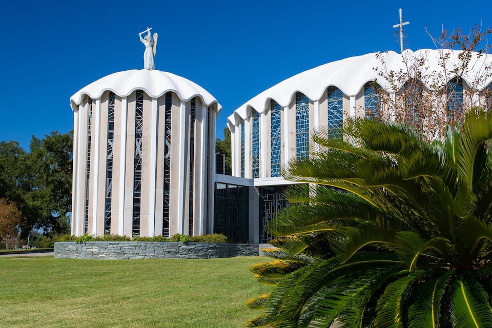 A modern building with two large domes and a statue on top.