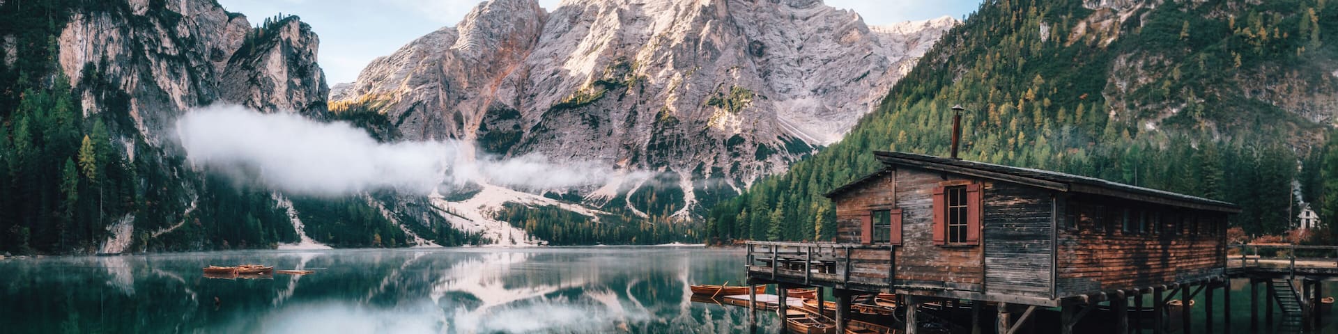 Panoramic view of Braies Lake with the hut and boats in Dolomites mountains and Seekofel in the morning, Sudtirol, Italy