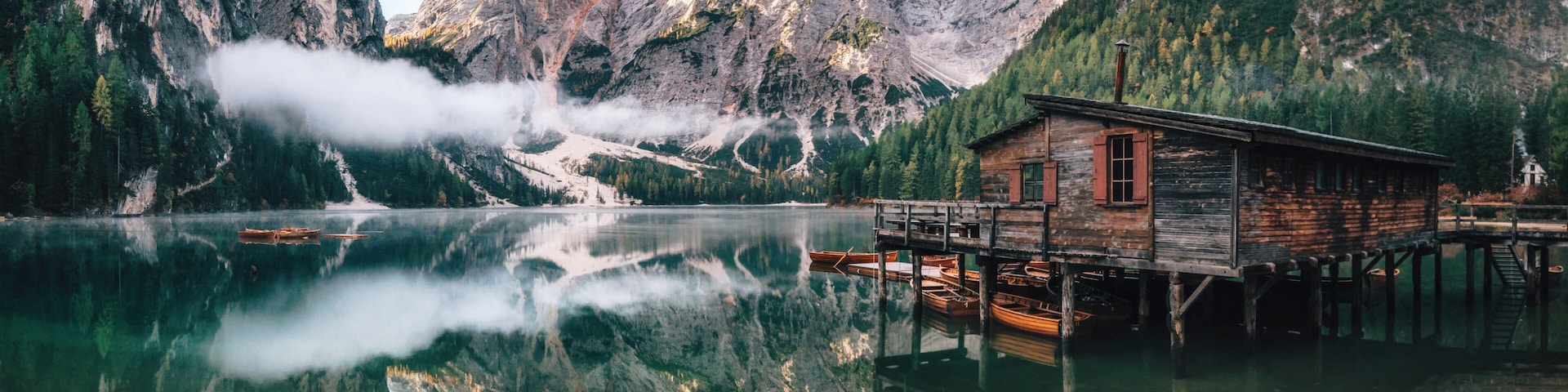 Panoramic view of Braies Lake with the hut and boats in Dolomites mountains and Seekofel in the morning, Sudtirol, Italy