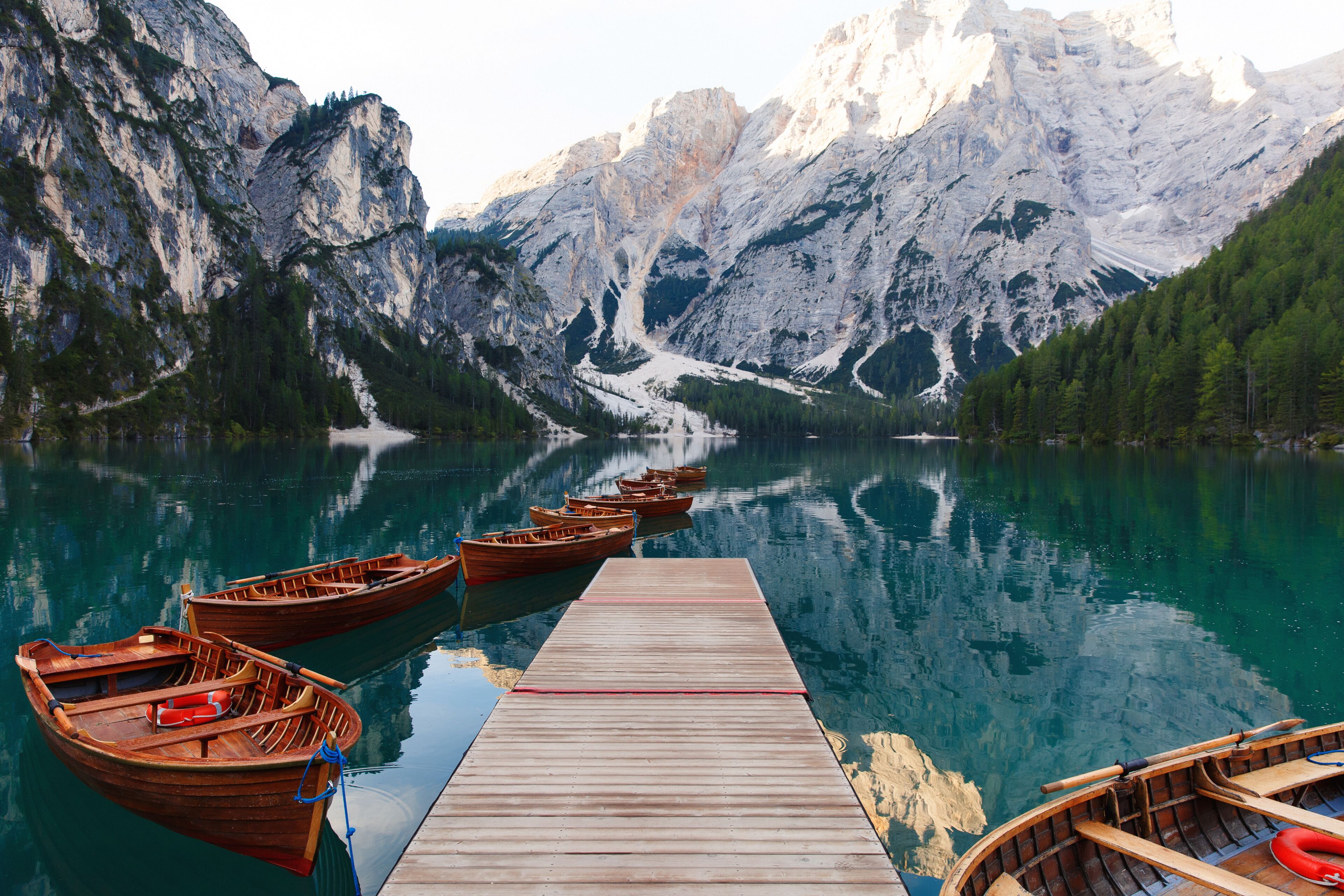 Un muelle de madera que conduce a un lago tranquilo rodeado de montañas.