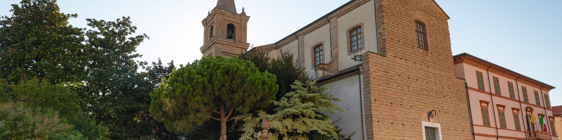 A historic square with a church tower, a fountain, and a statue.