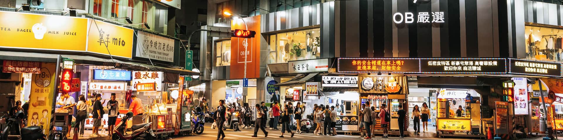 A busy urban street at night with illuminated billboards and storefronts.