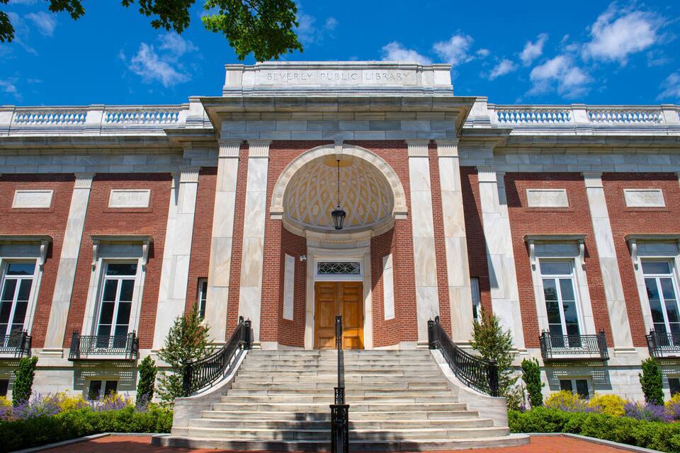 The Beverly Public Library with a grand entrance, steps, and a clear blue sky.