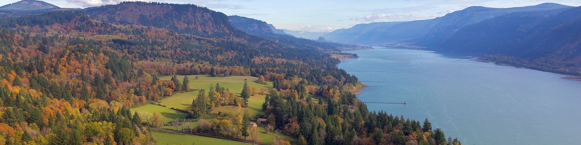 A lake surrounded by autumn-colored trees and rolling hills.