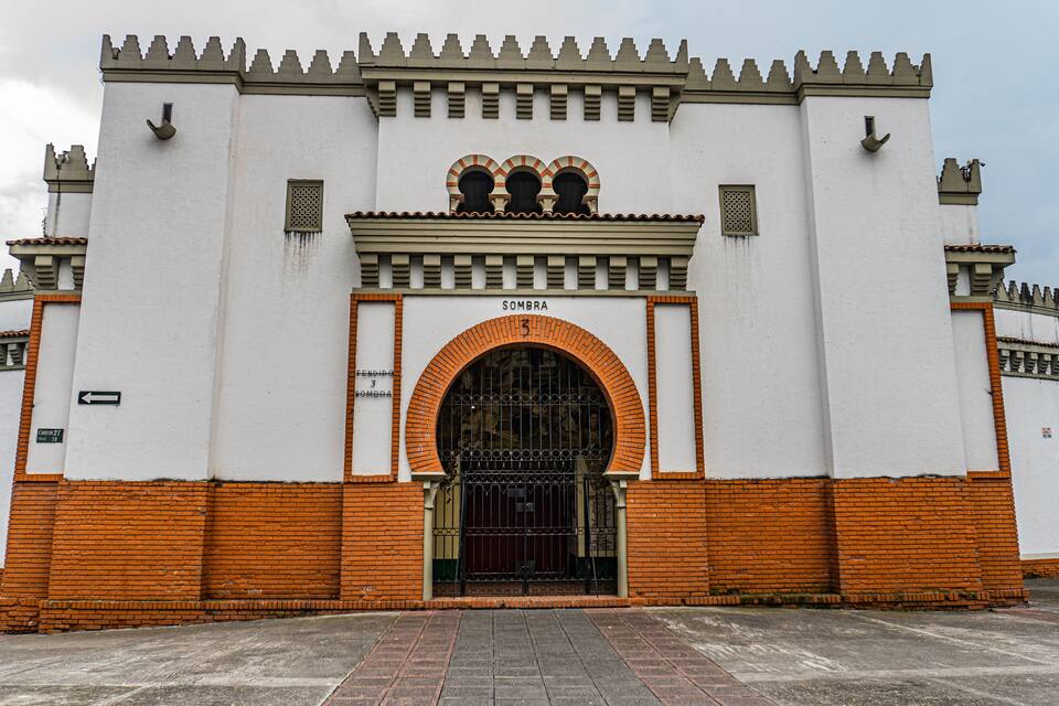 Un edificio con fachada blanca, base de ladrillo y un amplio acceso de arco.