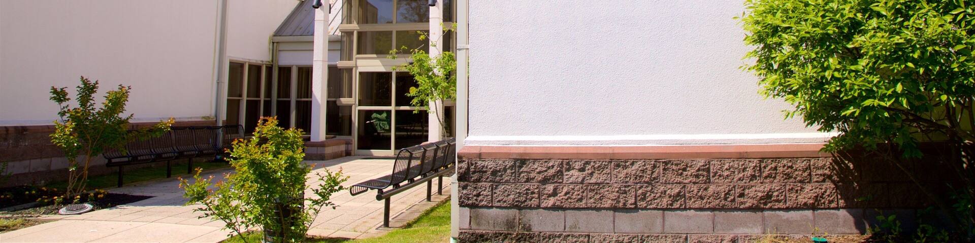 The exterior of the Benjamin Banneker Museum with a clear sky, a white building, and a small garden area with benches.