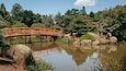 A red bridge over a calm pond surrounded by trees and rocks.