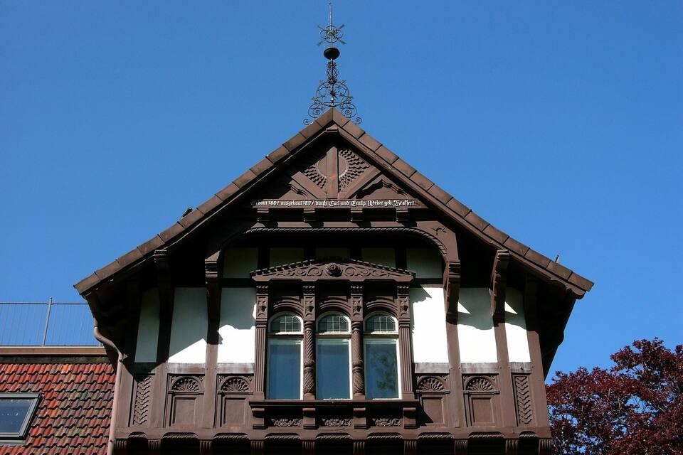 Un edificio con un tetto a forte spiovente, decorazioni in legno elaborate e una banderuola ornamentale.