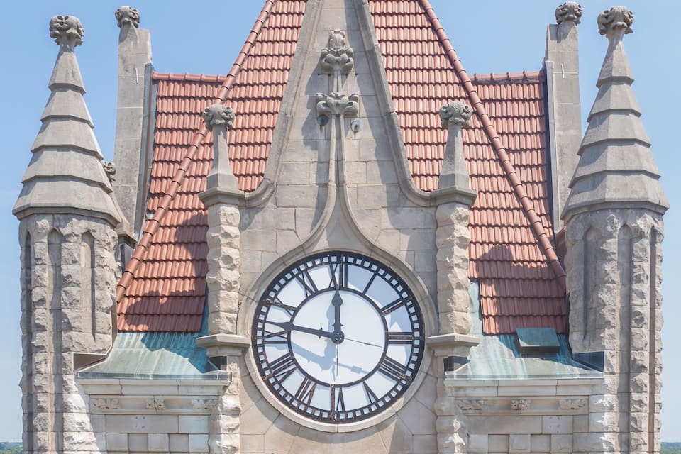 A historic building with a large clock, pointed roof, and stone gargoyles.