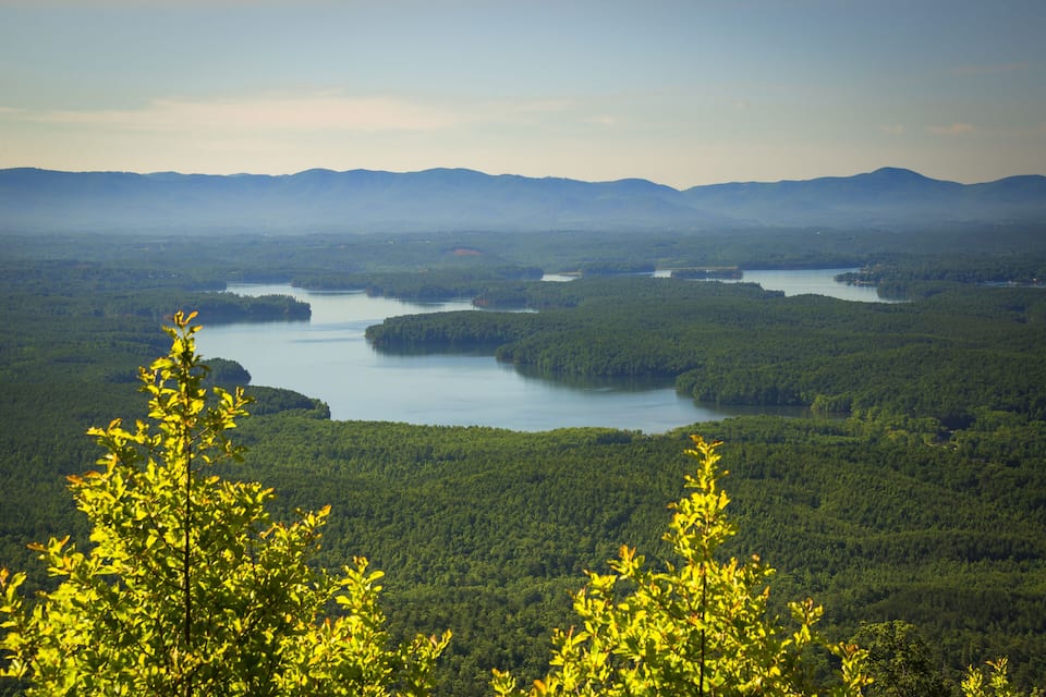 A landscape with multiple lakes surrounded by dense forests and distant mountains.