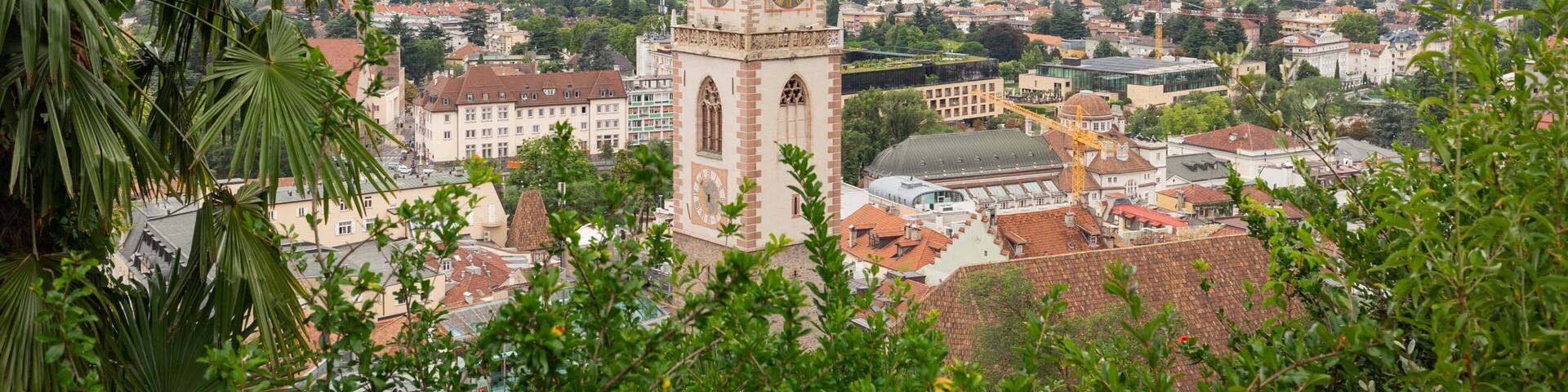 A clock tower in a town surrounded by mountains.