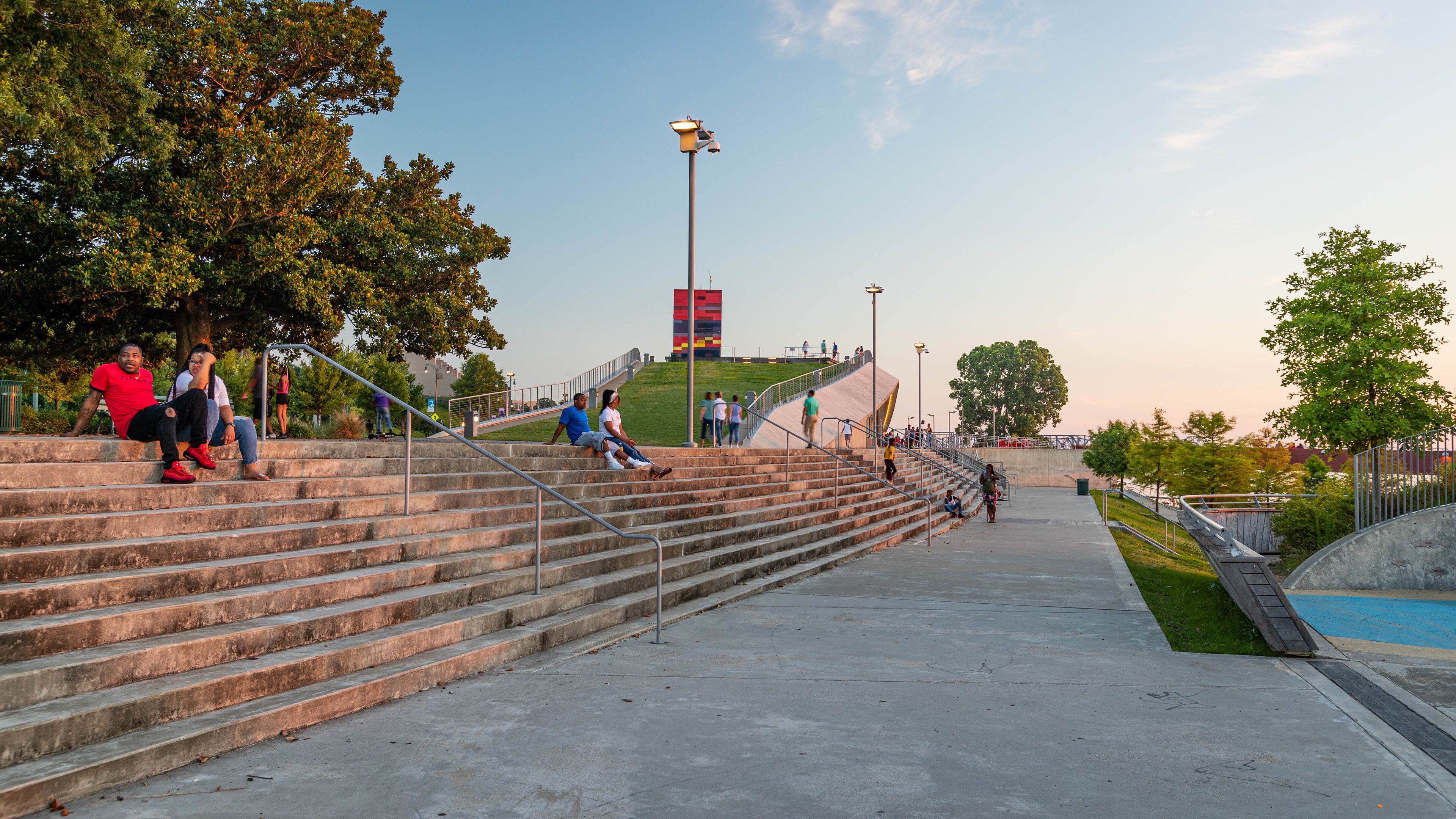 Un parque con escalones de hormigón, un asta de banderas y una piscina.