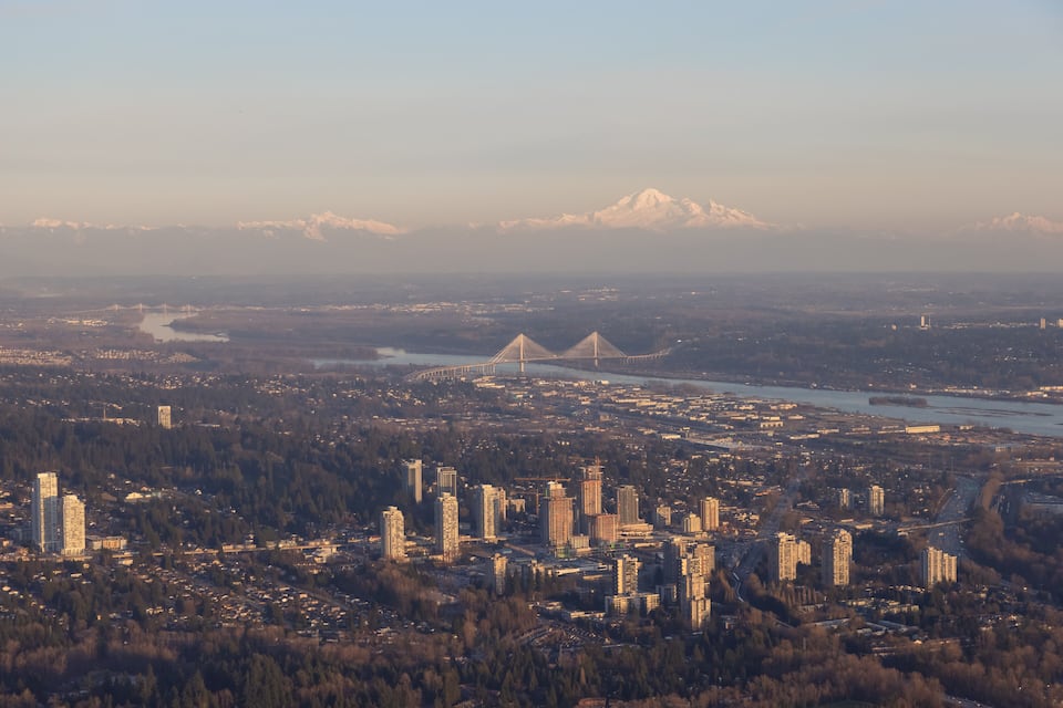 A cityscape with a river, a bridge, and snow-capped mountains in the background.