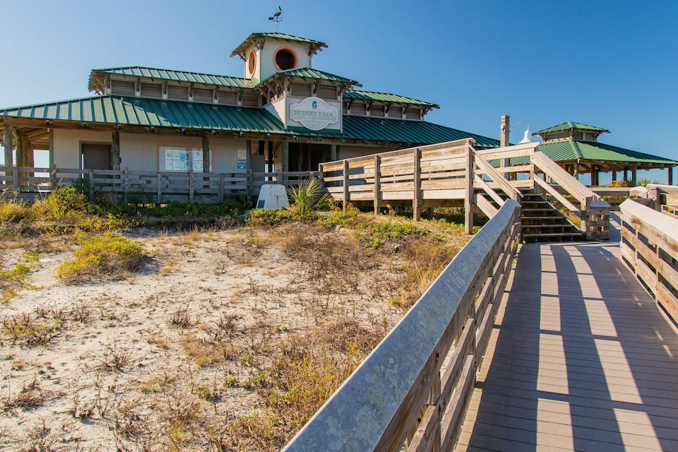 A wooden boardwalk leading to a park with a green roof and a sign reading "Beasley Park".