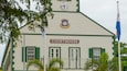 A courthouse with a clock, green shutters, and a coat of arms.