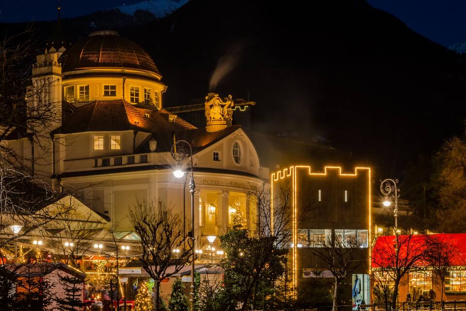 A historic building with a dome and a tower, surrounded by trees and illuminated by street lamps.
