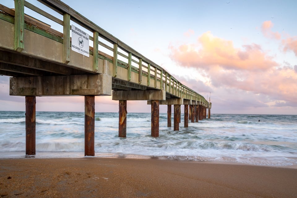 A pier extending into the ocean with a 'No-Dogs Allowed' sign.